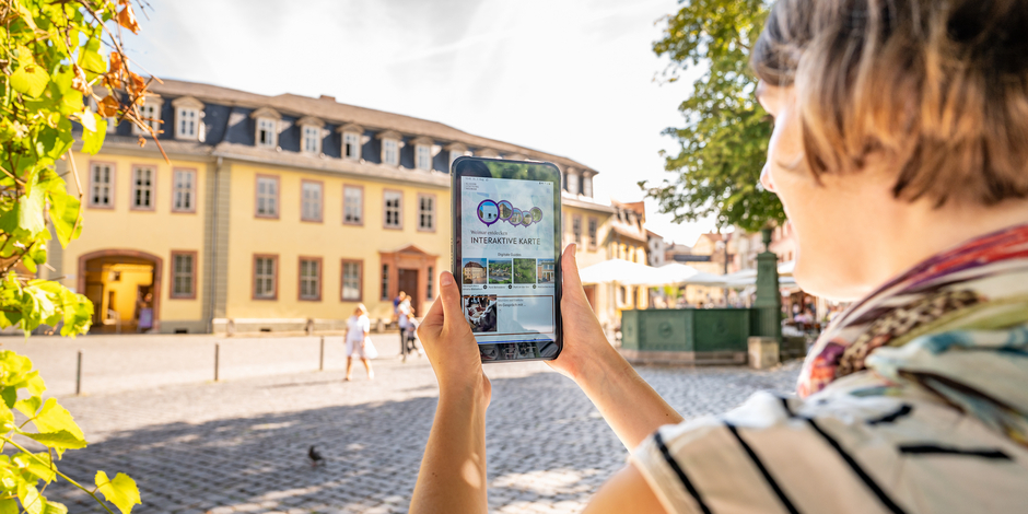 Weimar+ App Frau mit Tablet auf dem die App Weimar+ geöffnet ist