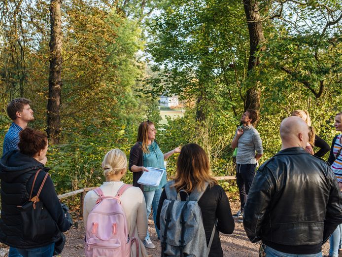Bildung und Vermittlung Gruppe Erwachsener steht um einen Guide in einer Parkkulisse