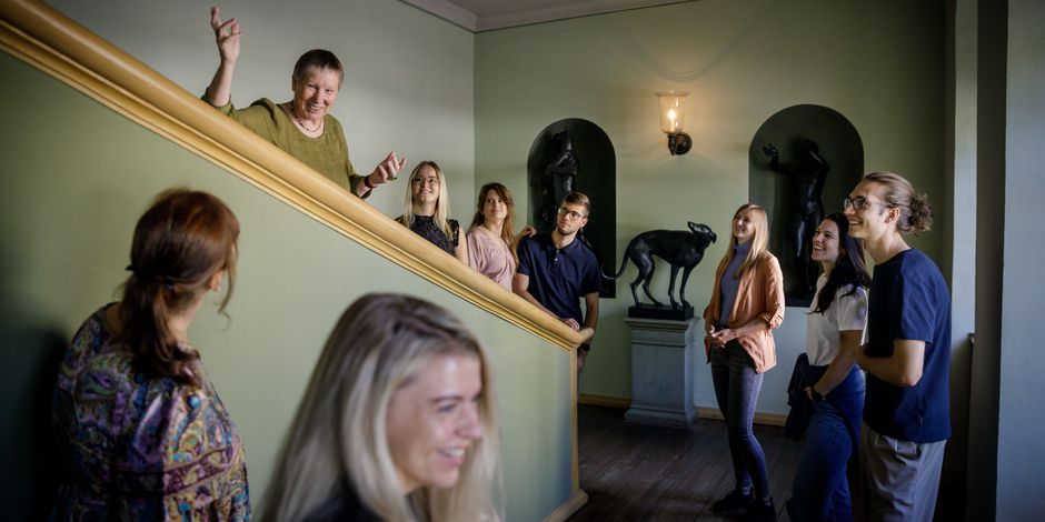 Eine Gruppe mit Guide macht einen Stopp auf einer Treppe, um Skulpturen und Gemälde zu betrachten