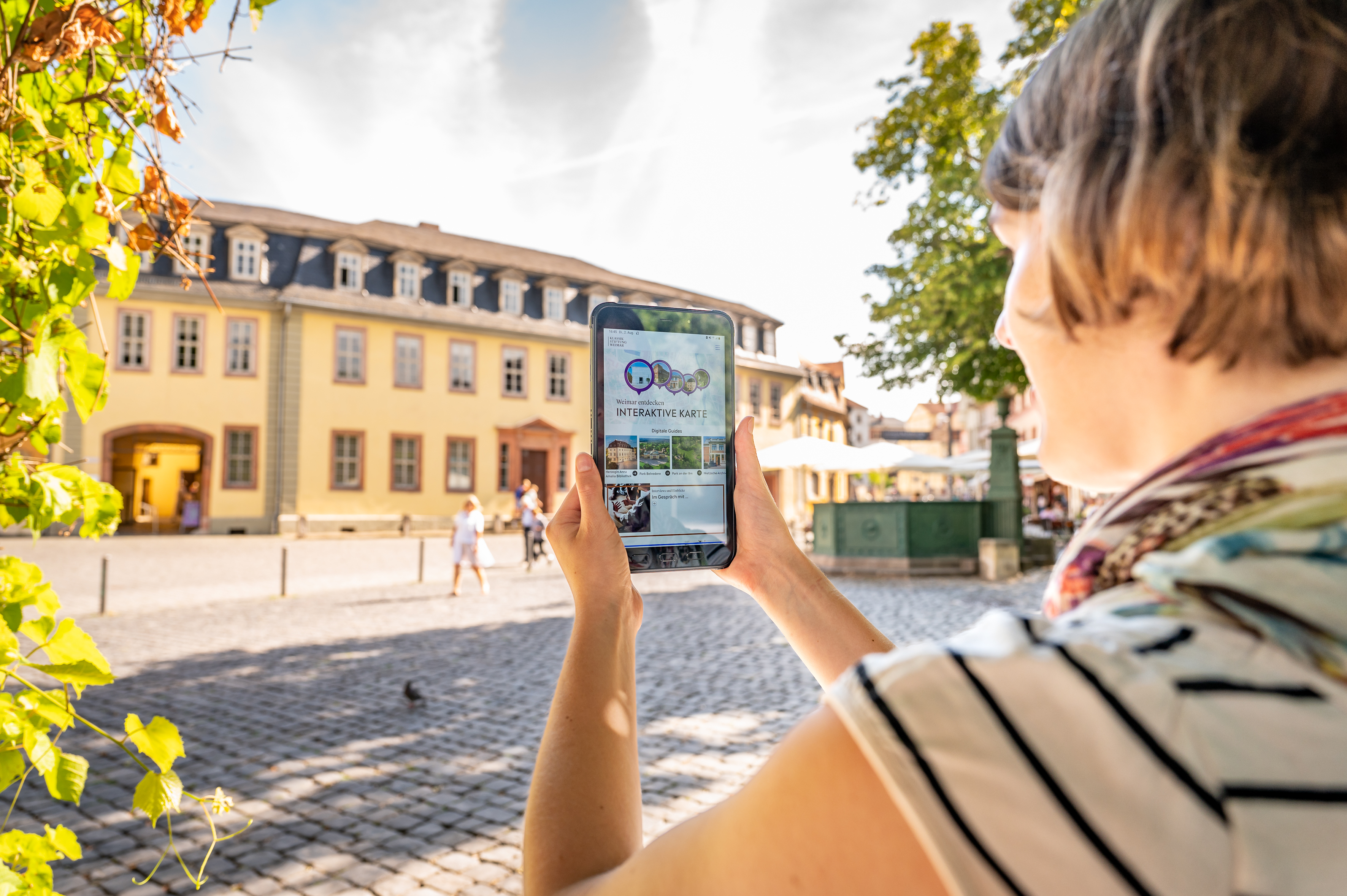 Weimar+ App Frau mit Tablet auf dem die App Weimar+ geöffnet ist