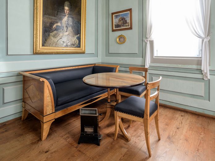 Schloss Tiefurt Ein Heizofen vor einem Sofa mit Tisch und Stühlen