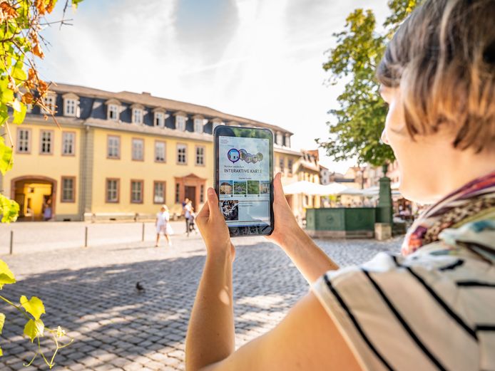 Weimar+ App Frau mit Tablet auf dem die App Weimar+ geöffnet ist