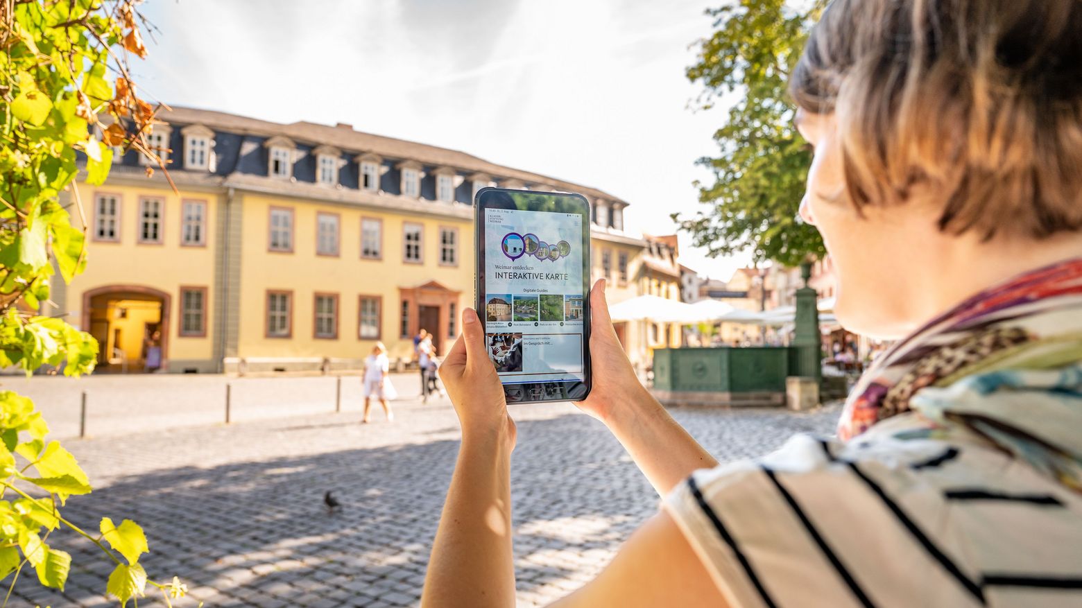 Weimar+ App Frau mit Tablet auf dem die App Weimar+ geöffnet ist