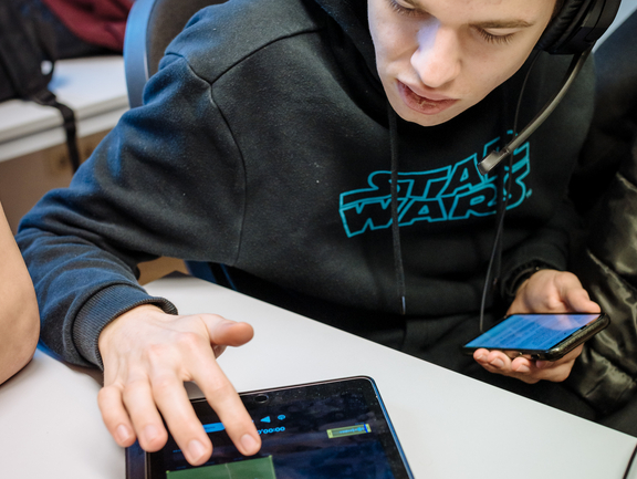 Berbeiten des kreativen Beitrags für Youpedia Ein Junge sitzt mit Kopfhörern am Tablet und bearbeitet eine Tonspur.