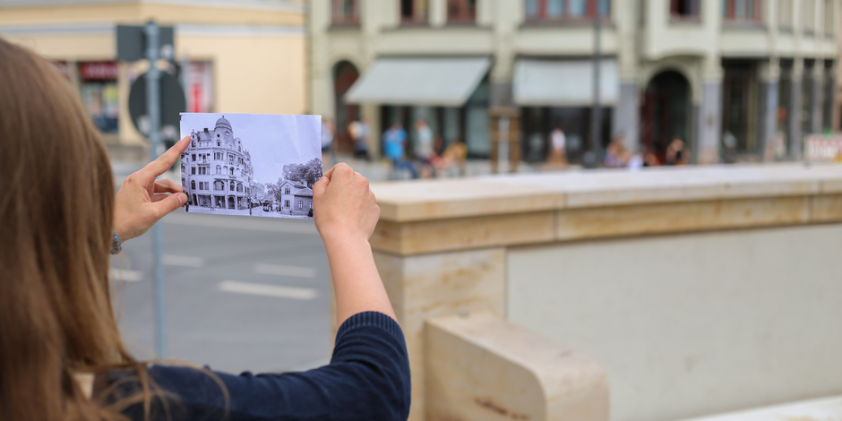 Frau hält historische Schwarz-Weiß-Fotografie vor ein Gebäude in Weimar.