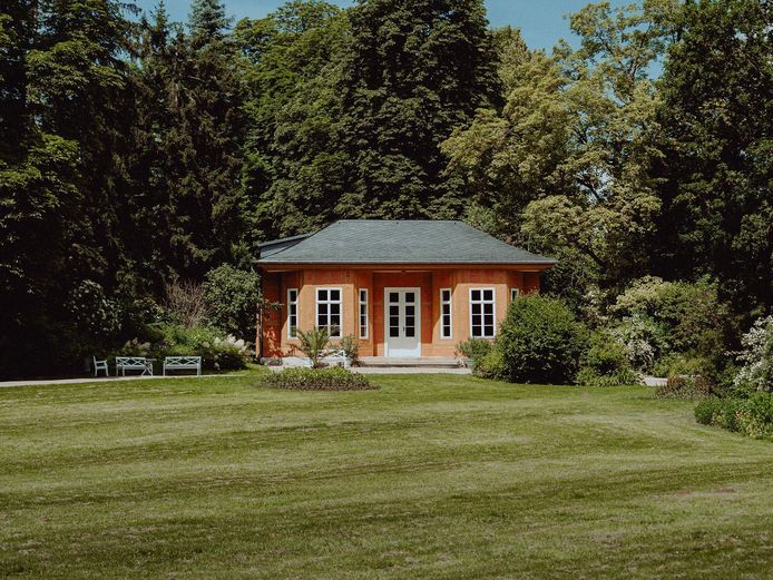 Teesalon im Schlosspark Tiefurt Bild von einem Pavillon umgeben von Bäumen und grüner Wiese.