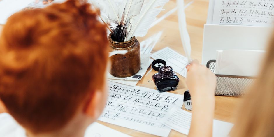 MACHT MIT! Werkstatt Ein Junge sitzt am Tisch und schreibt mit Federkiel und Tinte