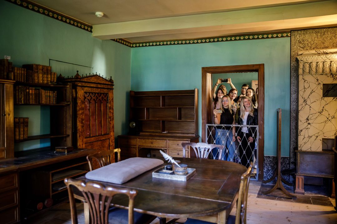 Photo of a study with writing utensils on the crowd of visitors that has gathered at the door frame