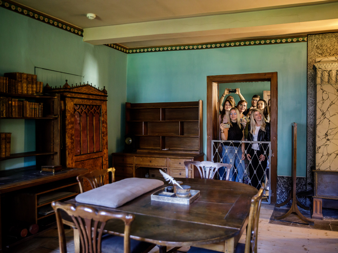 Foto vom einem Arbeitszimmer mit Schreibutensilien auf die Besuchermenge, die sich am Türrahmen eingefunden hat