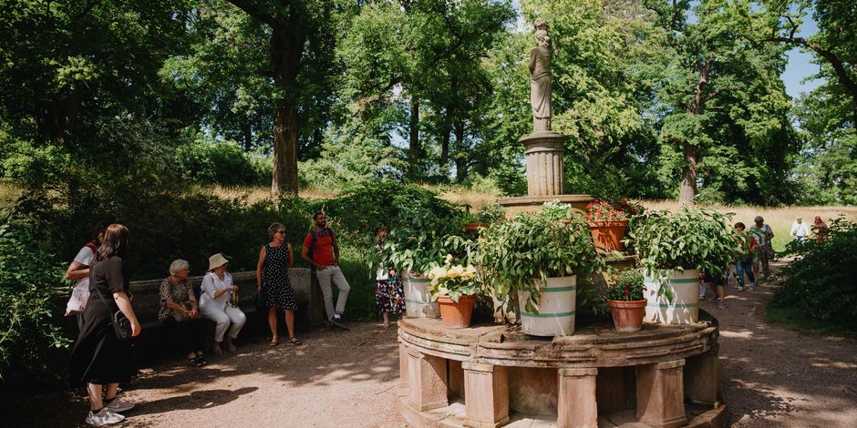 Eine Gruppe von Menschen schaut sich ein Denkmal im Park Belvedere an.