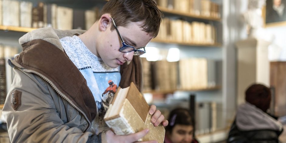 Barrierefreiheit in der Herzogin Anna Amalia Bibliothek Ein Junge mit Beeinträchtigungen untersucht ein Buch aus der historischen Bibliothek