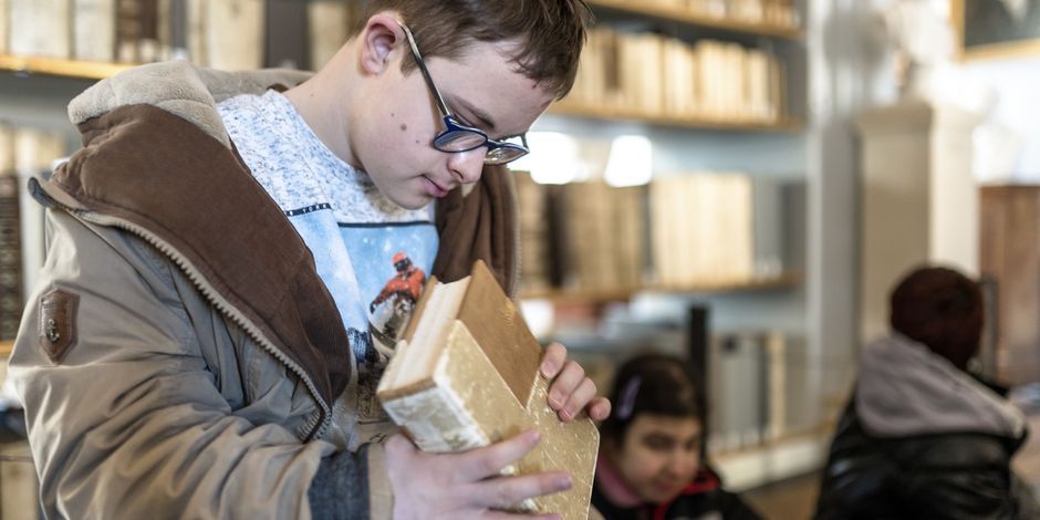 Accessibility in the Herzogin Anna Amalia Bibliothek A boy with disabilities examines a book from the historical library
