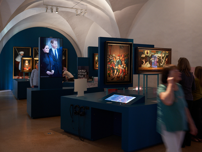 Cranachs Bilderfluten Ausstellungsraum mit Gewölbedecke, in dem verschiedene Gemäde hängen und sich Menschen bewegen.