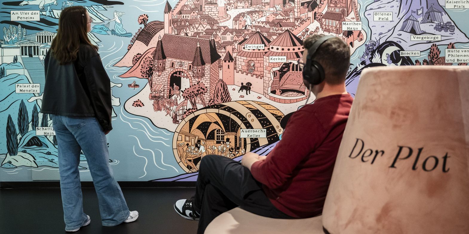 Faust. Eine Ausstellung Zwei-Menschen vor einer großen grafischen Wand mit Burganlage