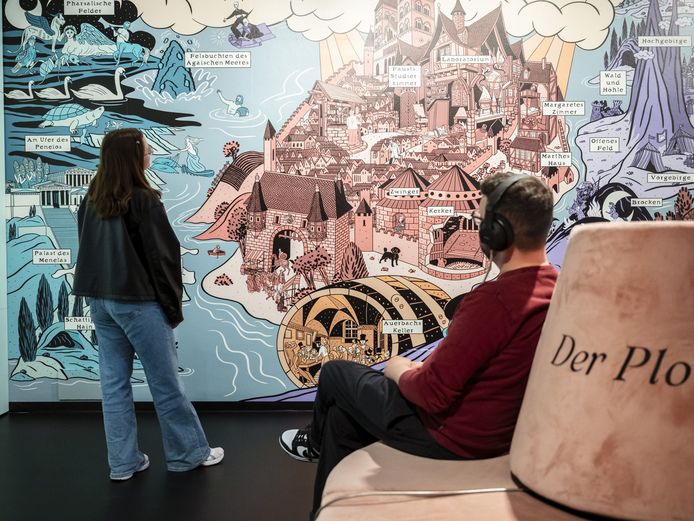 Faust. An exhibition Two people in front of a large graphic wall with a castle complex