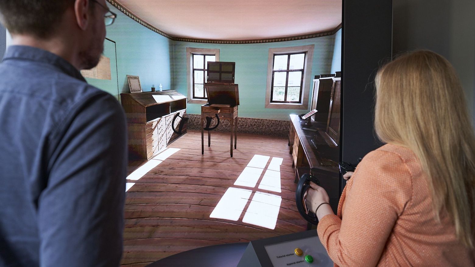 Goethe-Apparat im Betrieb Zwei Personen von Hinten stehen vor einem großen Screen und steuern mit Controllern in der Hand den Goethe-Apparat.