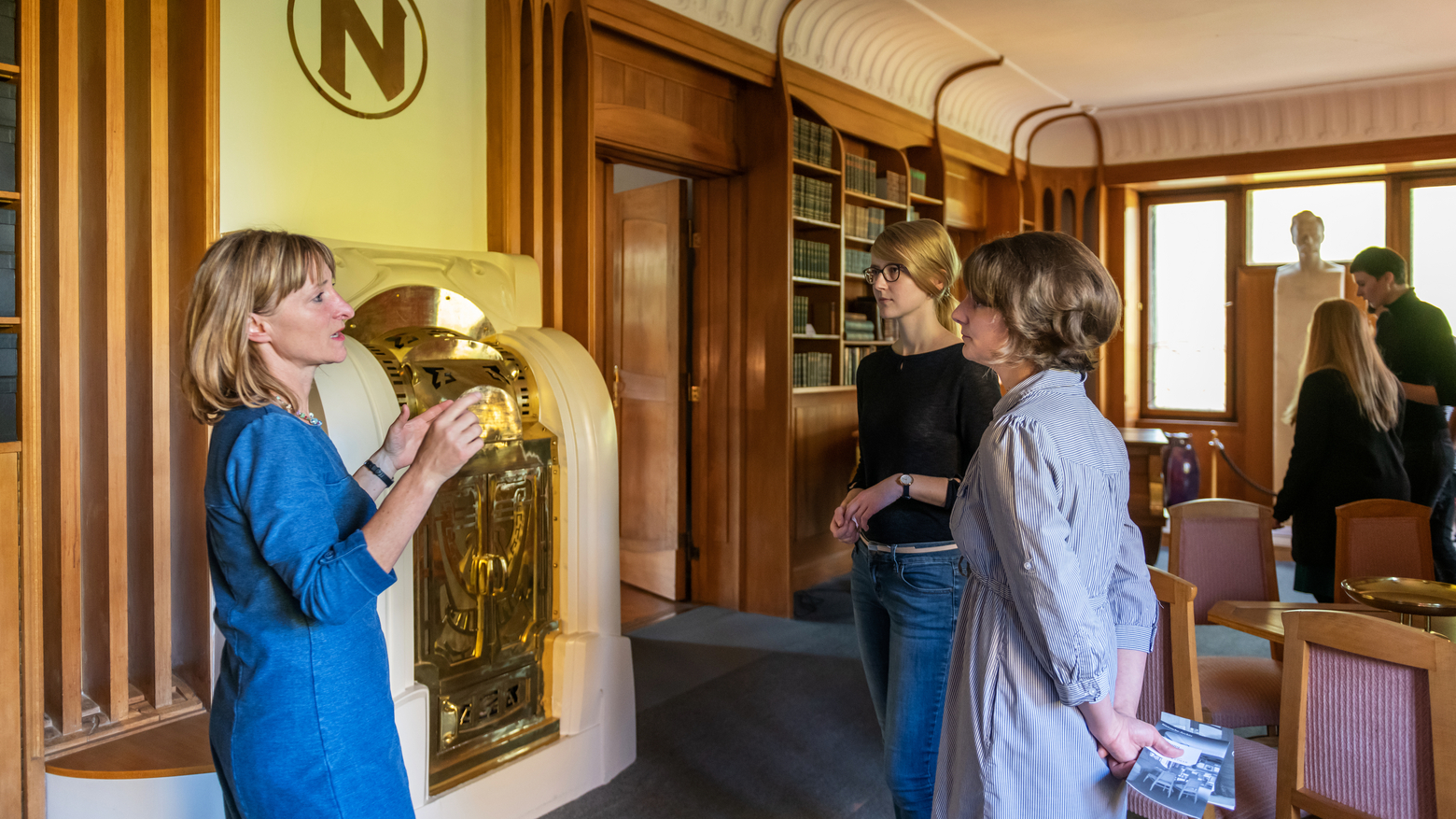 Bildung und Vermittlung Frau erklärt zwei Besucherinnen etwas zum Inventar im Nietzsche-Archiv