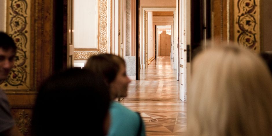 eine Gruppe flaniert durch hintereinanderliegende geöffnete Türbögen